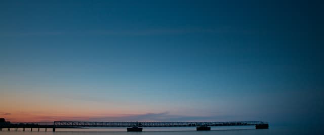 Lake Huron pier stretching into calm water at blue-hour twilight, pastel sky above
